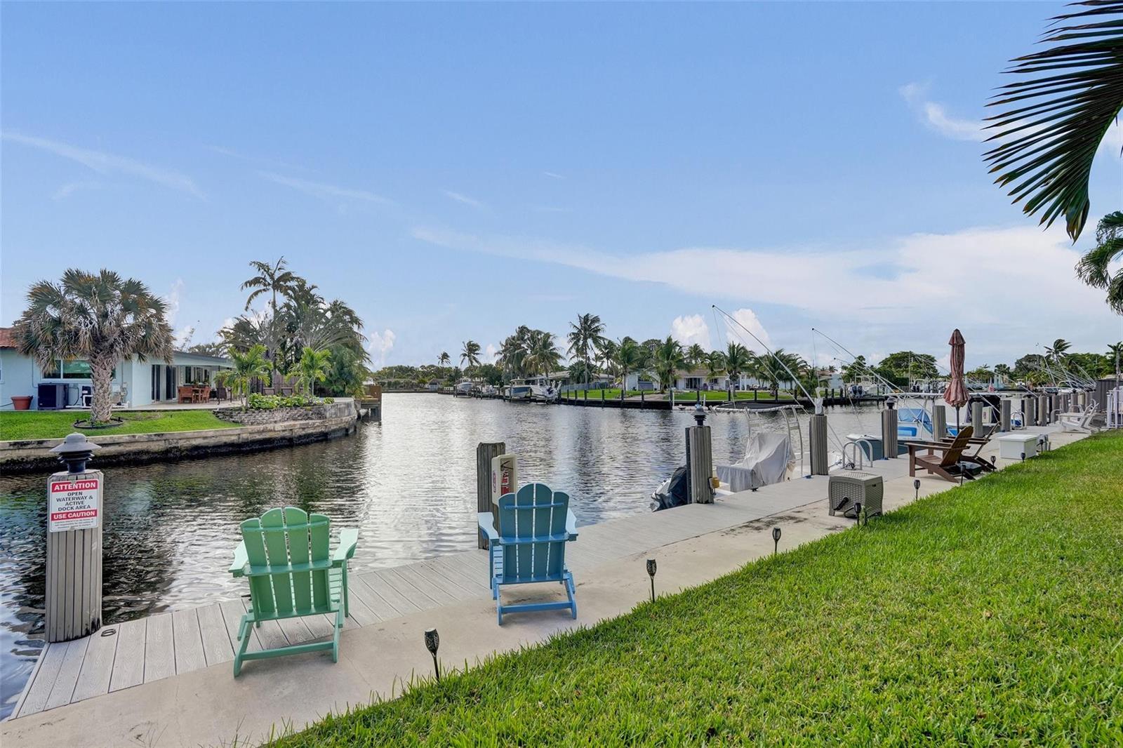 A concrete dock with two Adirondack chairs overlooks a canal lined with palm trees — 935 SE 9th Avenue # 16, Pompano Beach FL 33060, POMPANO BEACH, FL
