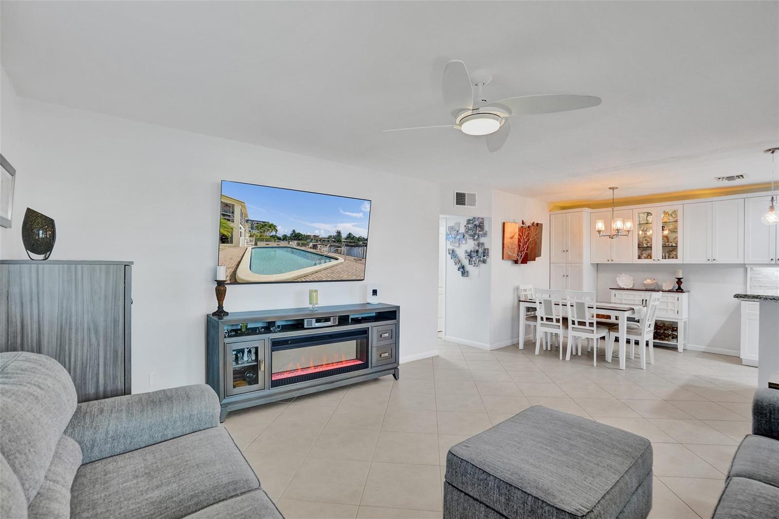 A living room with a fireplace console, wall-mounted television, and an adjacent dining area — 935 SE 9th Avenue # 16, Pompano Beach FL 33060, POMPANO BEACH, FL