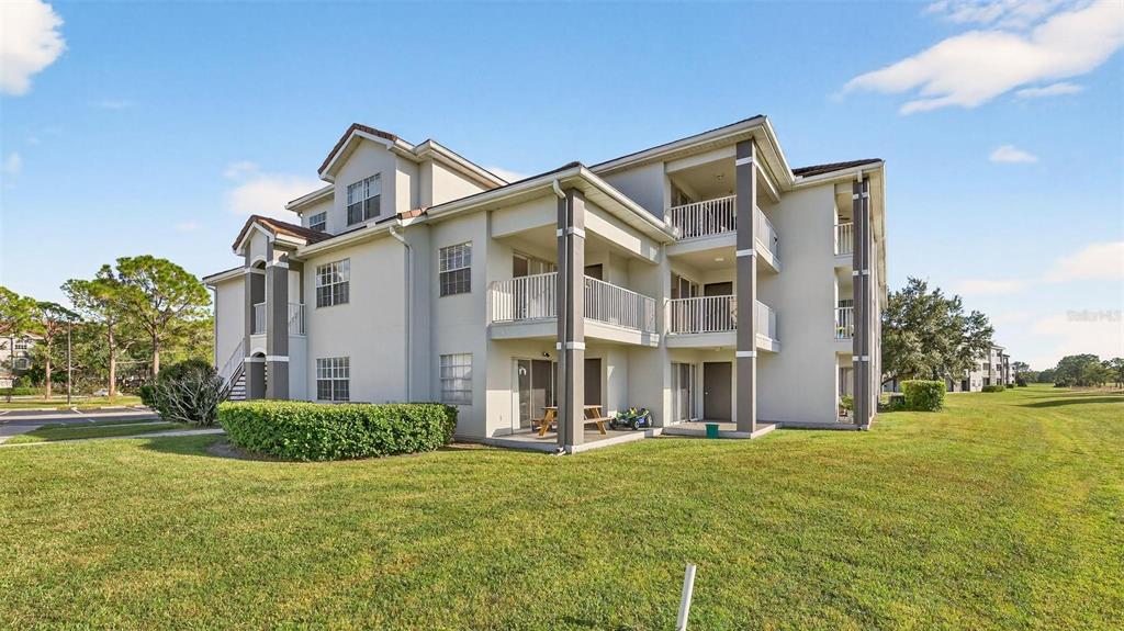 A three-story apartment building with balconies and a grassy lawn under a blue sky — 13917 FAIRWAY ISLAND DRIVE UNIT 928, ORLANDO, FL