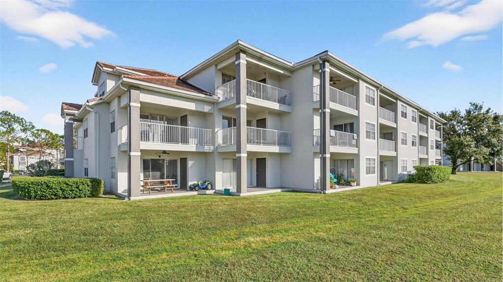 The exterior of a multi-story apartment building features balconies and a grassy lawn — 13917 FAIRWAY ISLAND DRIVE UNIT 928, ORLANDO, FL