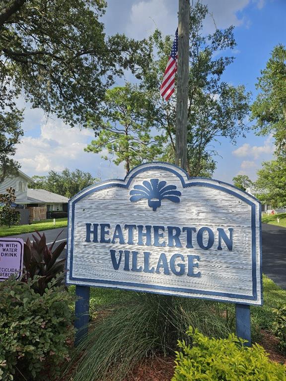 A blue and white sign for Heatherton Village stands outdoors beneath an American flag — 619 HEATHERTON VILLAGE, ALTAMONTE SPRINGS, FL
