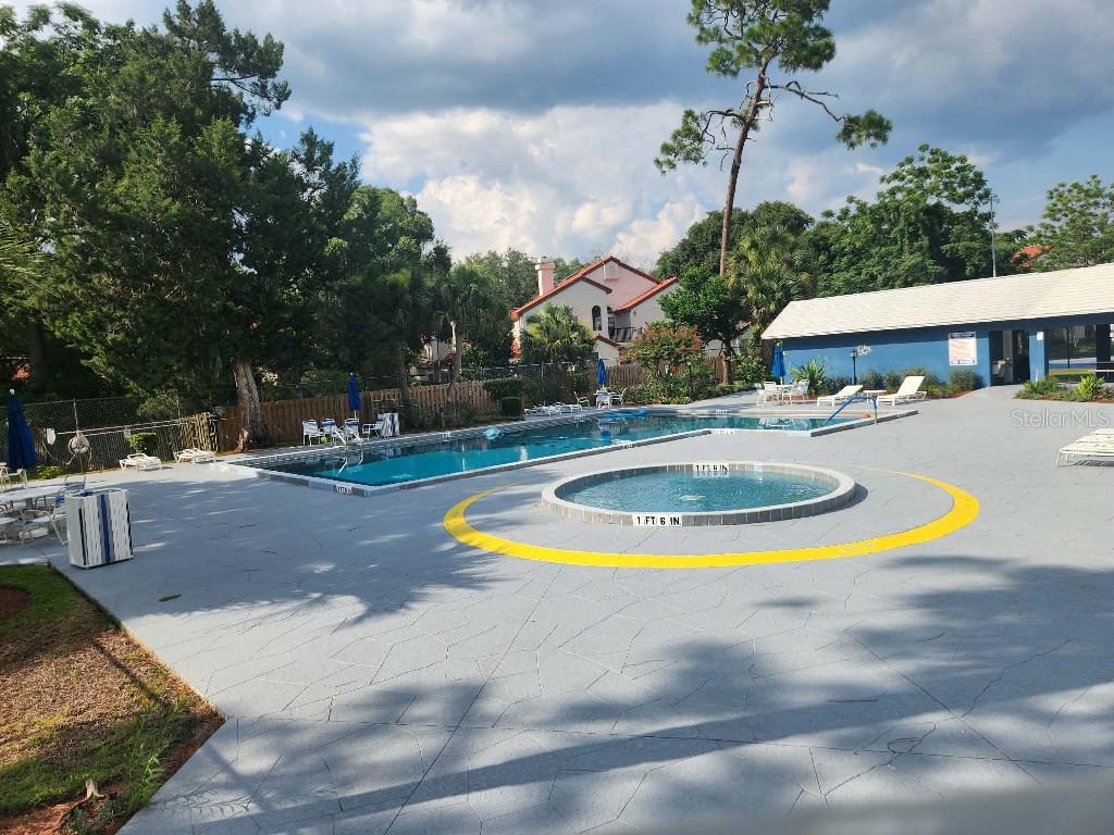A rectangular swimming pool and a circular spa are set in a paved pool deck — 619 HEATHERTON VILLAGE, ALTAMONTE SPRINGS, FL