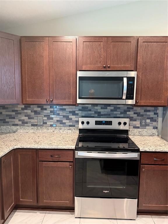 A kitchen features dark wood cabinets, a stainless steel microwave, and a matching electric range — 3770 SE 137TH LANE, SUMMERFIELD, FL