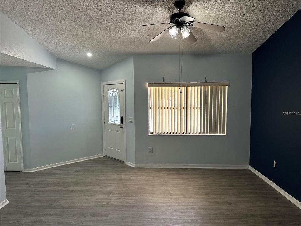 A living room features light blue walls, a dark accent wall, and gray wood flooring — 214 MAGELLAN DRIVE, KISSIMMEE, FL