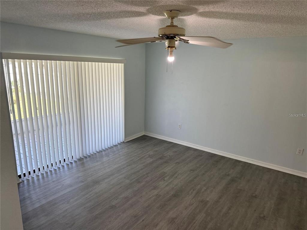 An empty room features light blue walls, gray wood-look flooring, and a ceiling fan — 214 MAGELLAN DRIVE, KISSIMMEE, FL