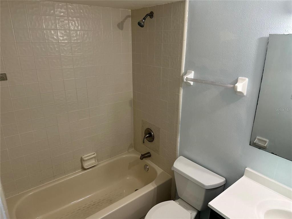 A bathroom features a beige bathtub with a showerhead, a white toilet, and a vanity — 214 MAGELLAN DRIVE, KISSIMMEE, FL