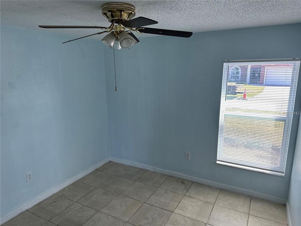 A bedroom with light blue walls, tile flooring, a ceiling fan, and a window — 214 MAGELLAN DRIVE, KISSIMMEE, FL