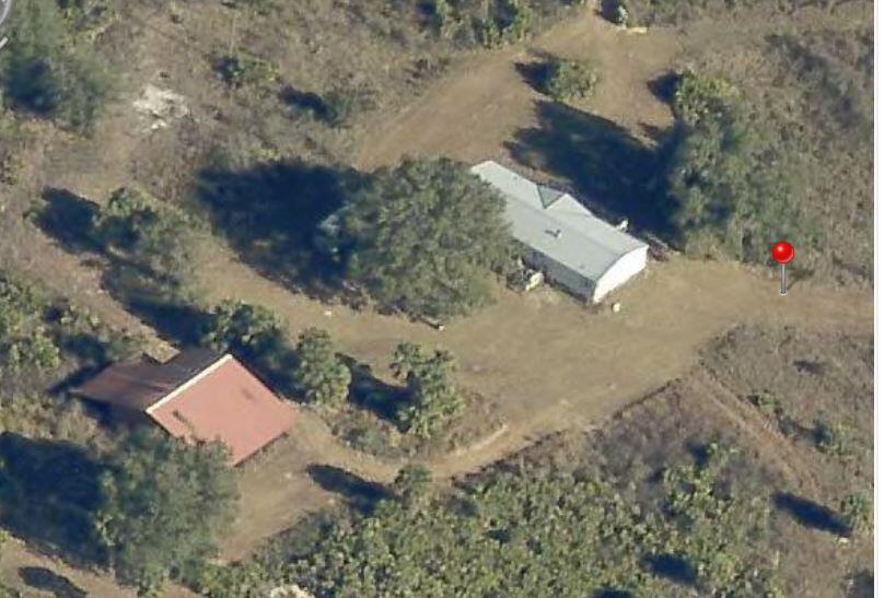 An aerial view shows two buildings with metal roofs situated on a rural, wooded lot — 18420 NW 278 Street, Okeechobee FL 34972, OKEECHOBEE, FL