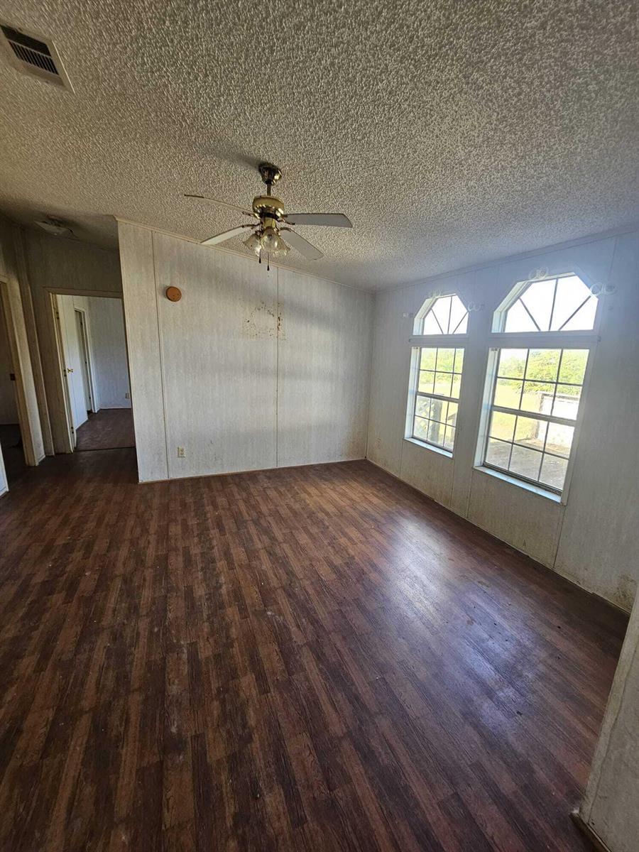 An empty room with wood-look flooring, a ceiling fan, and two arched windows — 18420 NW 278 Street, Okeechobee FL 34972, OKEECHOBEE, FL