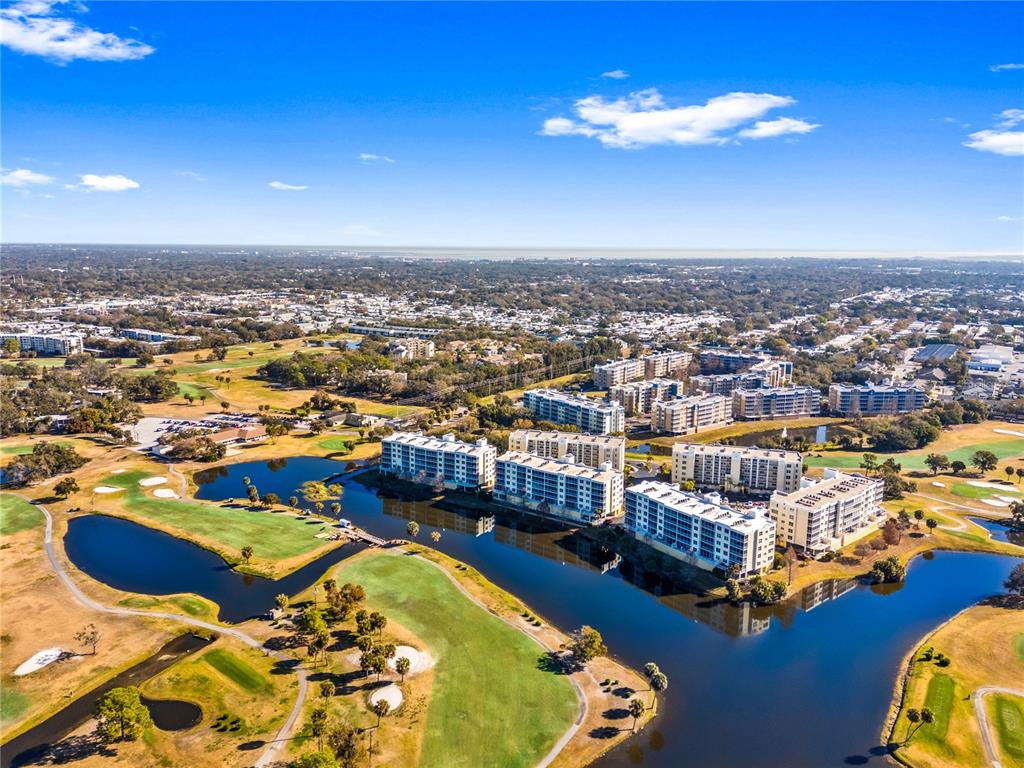 An aerial view shows multi-story apartment buildings situated along a lake and golf course — 1200 COUNTRY CLUB DRIVE UNIT 1404, LARGO, FL
