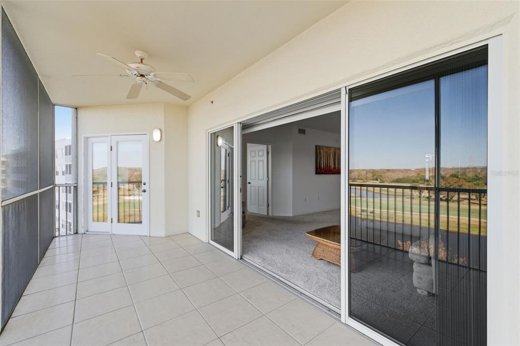 A tiled balcony with a ceiling fan overlooks a golf course through a sliding door — 1200 COUNTRY CLUB DRIVE UNIT 1404, LARGO, FL