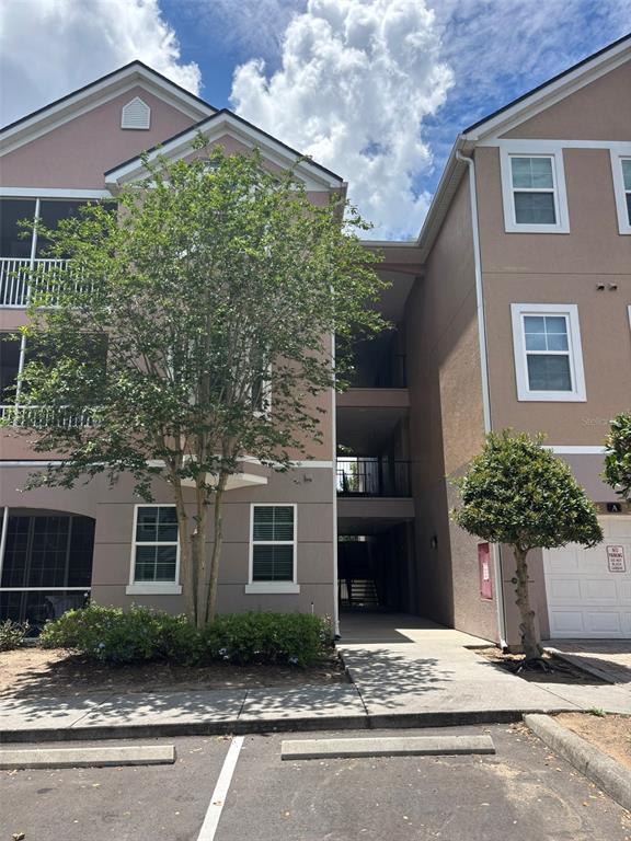 Exterior view of a multi-story residential building with a central breezeway and parking spaces — 3468 SOHO STREET UNIT 303, ORLANDO, FL