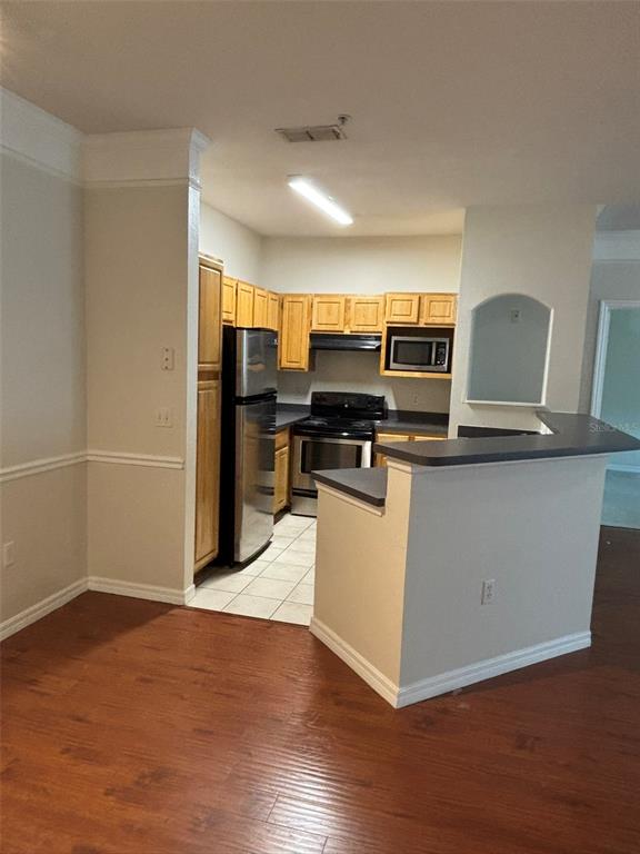 A kitchen with wooden cabinets, stainless steel appliances, and a breakfast bar — 3468 SOHO STREET UNIT 303, ORLANDO, FL