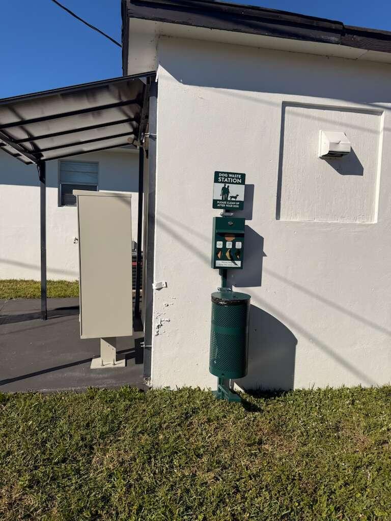 A dog waste station with a bag dispenser and trash bin is mounted on a wall — 1885 40th Avenue # 5, Vero Beach FL 32960, VERO BEACH, FL