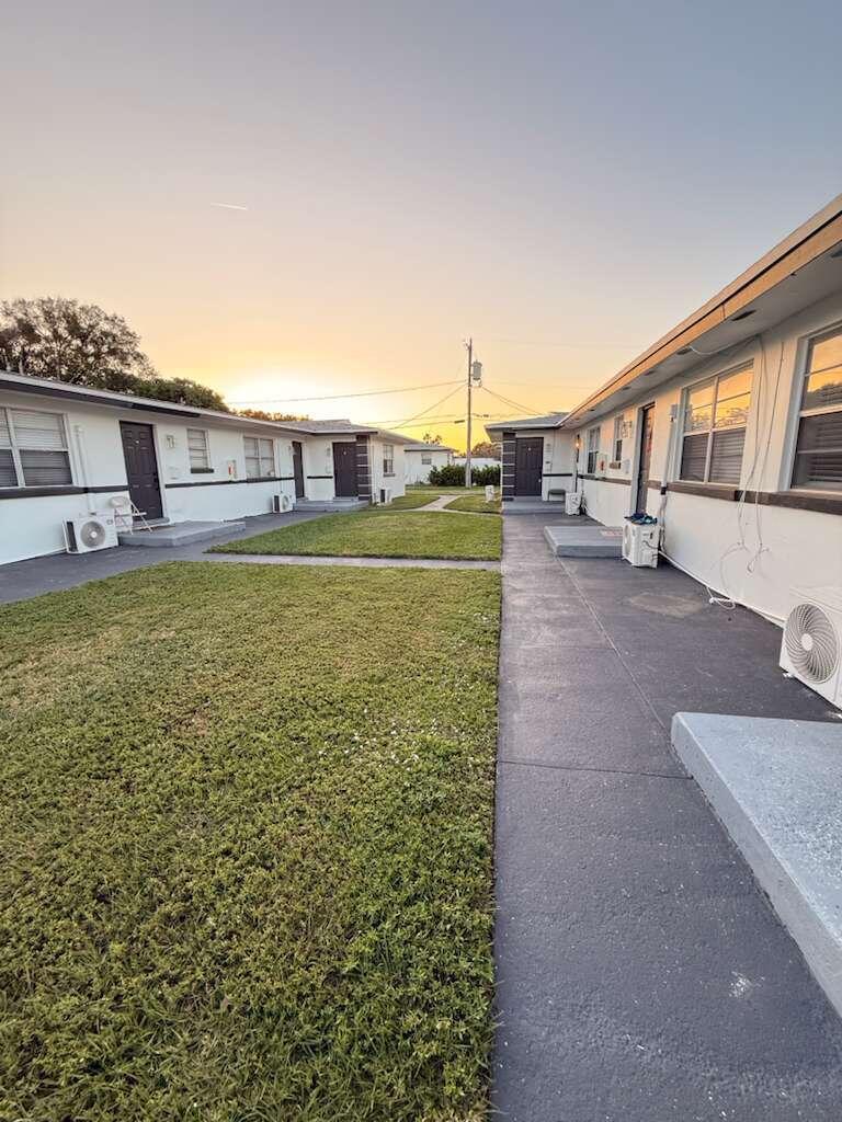 Exterior view of a single-story apartment complex with a central lawn and paved walkways — 1885 40th Avenue # 5, Vero Beach FL 32960, VERO BEACH, FL