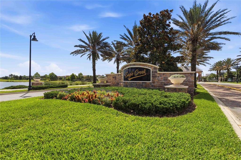 A stone monument sign for Eagle Creek sits in a landscaped yard with palm trees — 10096 SUNNIFA ALLEY, ORLANDO, FL