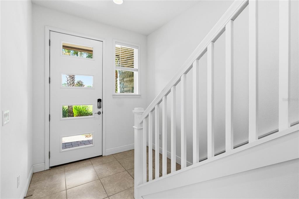 An entryway features a white front door with four glass panels, tile flooring, and stairs — 10096 SUNNIFA ALLEY, ORLANDO, FL