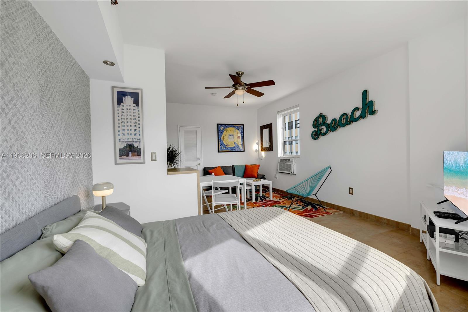 A studio apartment features a bed, a small dining area, and a large wall sign — 255 W 24th St # 542, Miami Beach FL 33140, MIAMI BEACH, FL