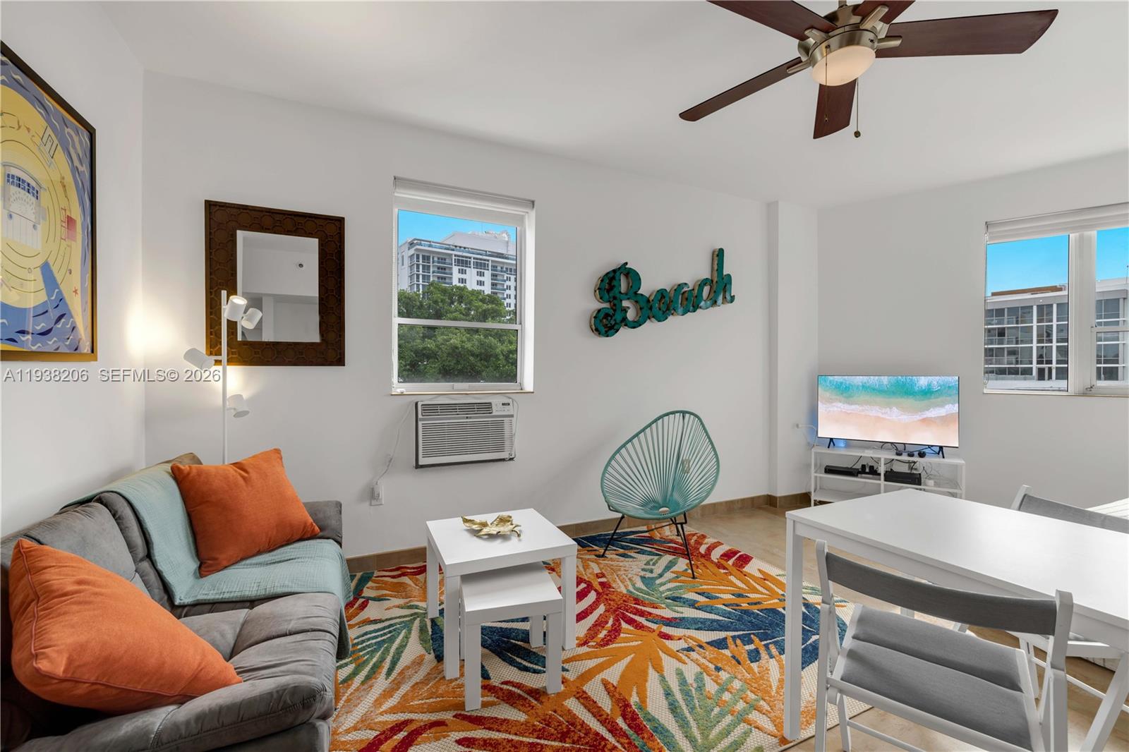 A living room features a grey sofa, a colorful area rug, and a dining table — 255 W 24th St # 542, Miami Beach FL 33140, MIAMI BEACH, FL