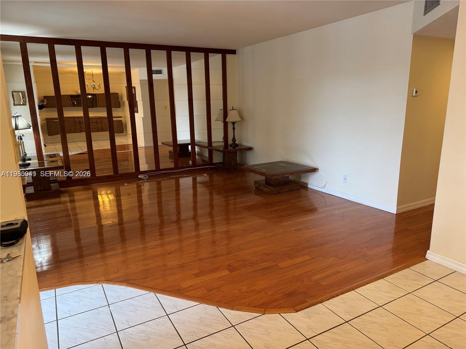 A dining area features wall-mounted wooden cabinetry, a chandelier, and a mix of tile and hardwood flooring — 100 SE 6th Ave # 207, Pompano Beach FL 33060, POMPANO BEACH, FL