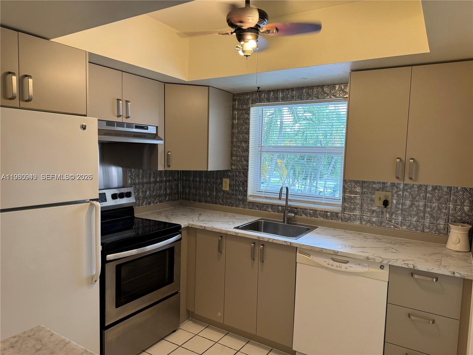 A living room features hardwood flooring, a tiled entryway, and a mirrored wall with slats — 100 SE 6th Ave # 207, Pompano Beach FL 33060, POMPANO BEACH, FL