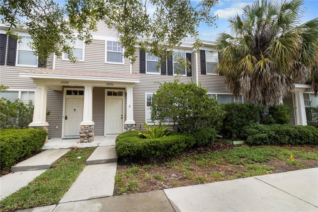 A two-story townhouse exterior features light gray siding, white trim, and a shared covered porch — 12294 COUNTRY WHITE CIRCLE, TAMPA, FL