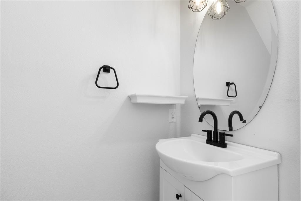 A bathroom features a white vanity, a black faucet, an oval mirror, and a shelf — 12294 COUNTRY WHITE CIRCLE, TAMPA, FL