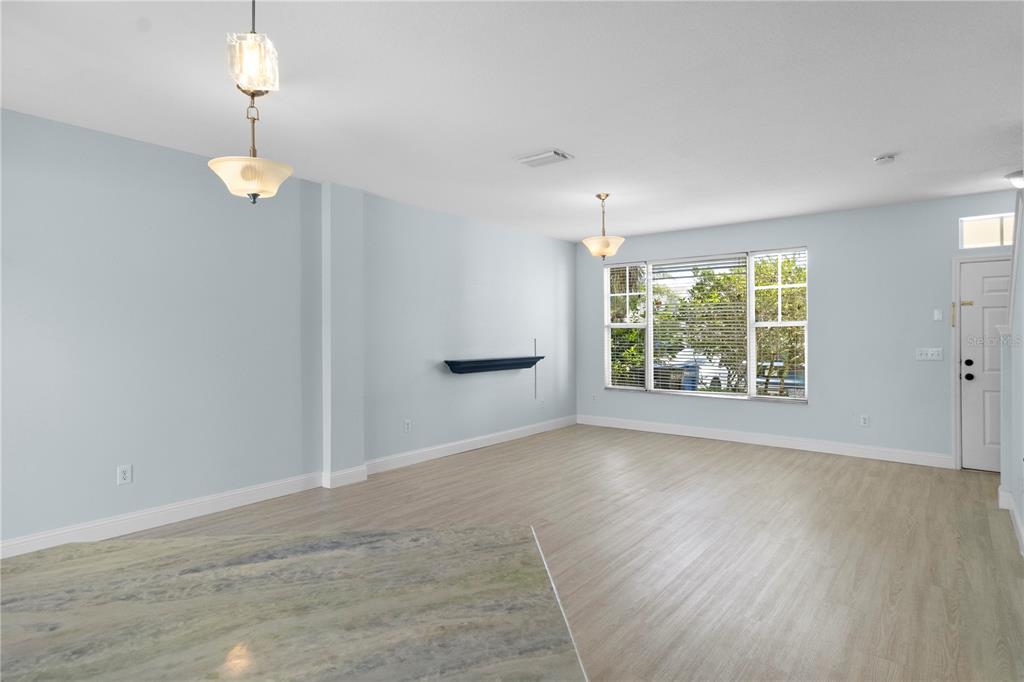 An open living area features light blue walls, wood-look flooring, two pendant lights, and windows — 12294 COUNTRY WHITE CIRCLE, TAMPA, FL