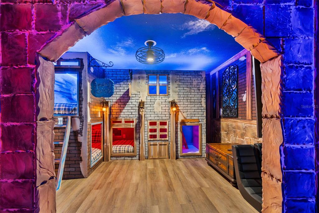 A themed bedroom features built-in bunk beds, brick-style walls, and a painted sky ceiling — 1187 KINGSBARN STREET, DAVENPORT, FL