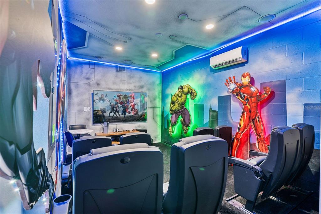 A themed home theater features rows of black chairs, a large television, and superhero wall murals — 1187 KINGSBARN STREET, DAVENPORT, FL