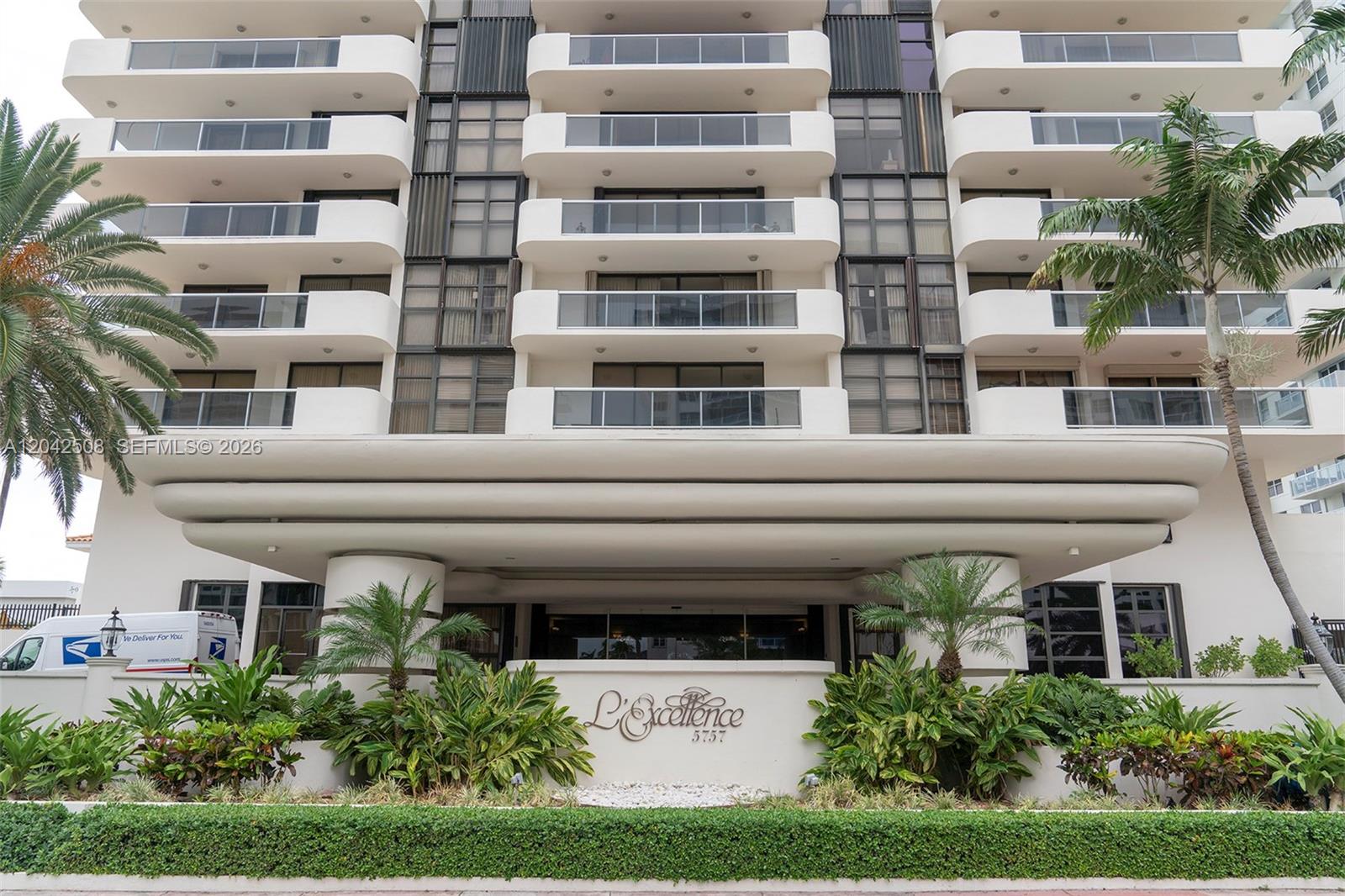 The exterior of a multi-story apartment building features balconies, palm trees, and a landscaped entrance — 5757 Collins Ave # 1604, Miami Beach FL 33140, MIAMI BEACH, FL