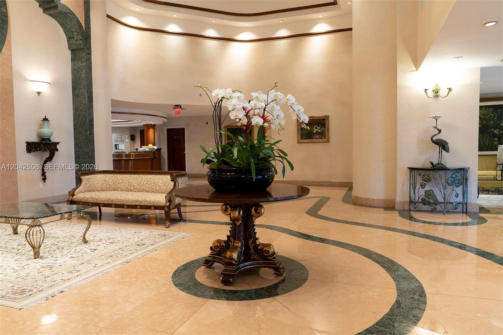 A spacious lobby features a central floral arrangement, marble flooring, and ornate furniture — 5757 Collins Ave # 1604, Miami Beach FL 33140, MIAMI BEACH, FL