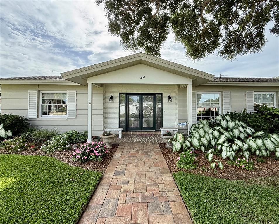 A single-story house with light siding, a paved walkway, and a covered front entryway — 1853 PARADISE LANE, CLEARWATER, FL