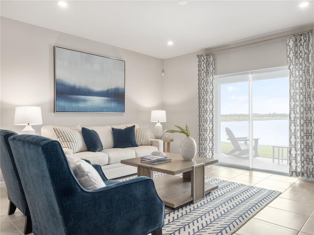 A living room features a white sofa, blue armchairs, a coffee table, and sliding glass doors — 384 BALI STREET, LADY LAKE, FL