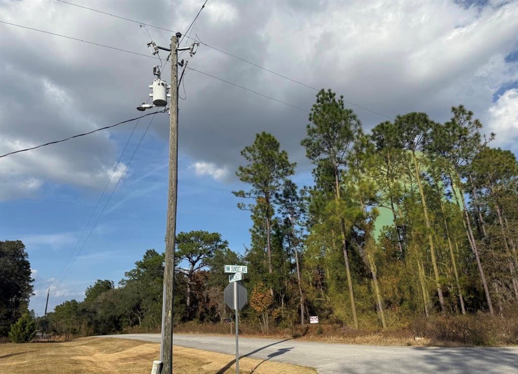 A utility pole stands at a street corner near a wooded lot under a cloudy sky — 0 SUNSET AVENUE NW, DUNNELLON, FL