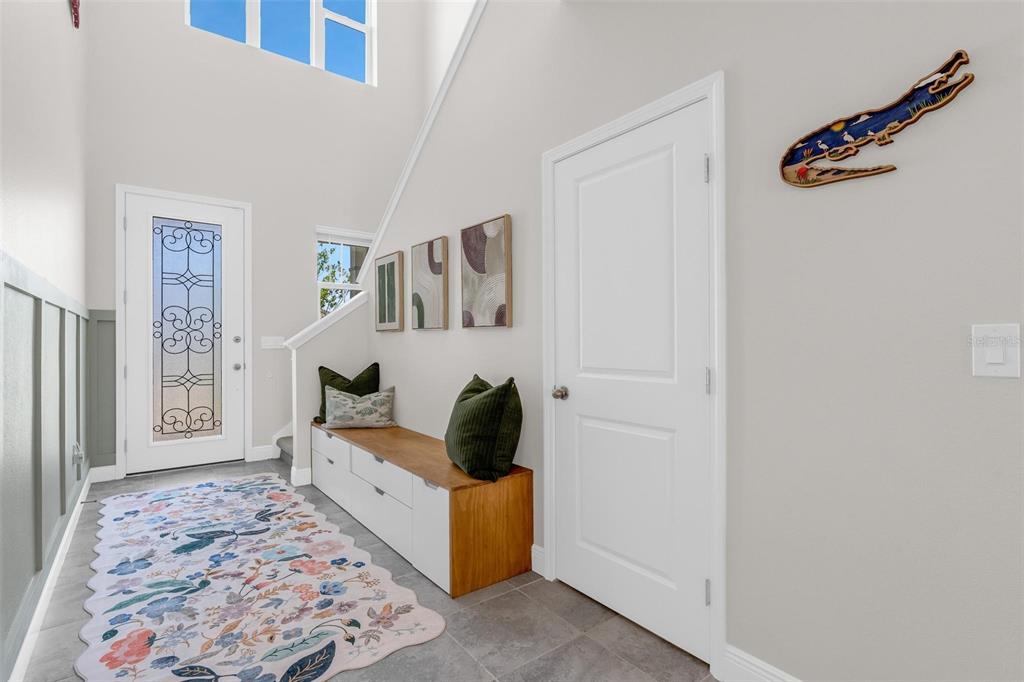 An entryway features a white door with glass, a wooden storage bench, and a floral rug — 2019 SUNSHINE PEAK DRIVE, MINNEOLA, FL
