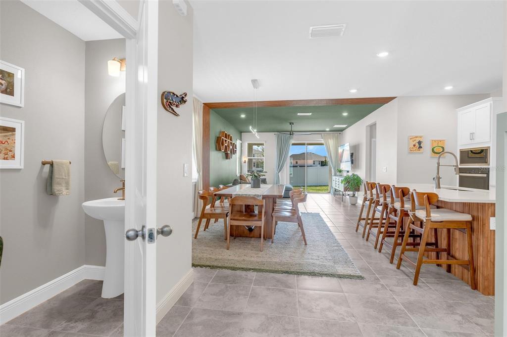 A view from a small bathroom looking into an open-concept dining area and kitchen — 2019 SUNSHINE PEAK DRIVE, MINNEOLA, FL
