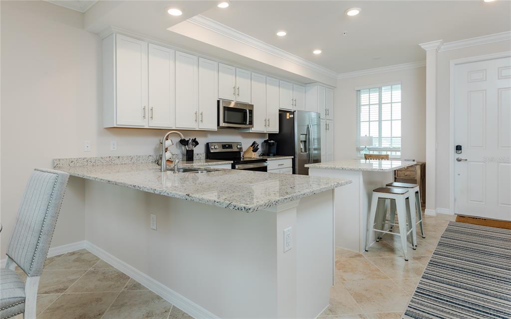 A kitchen features white cabinets, granite countertops, stainless steel appliances, and a breakfast bar — 43030 GREENWAY BOULEVARD UNIT 435, PUNTA GORDA, FL