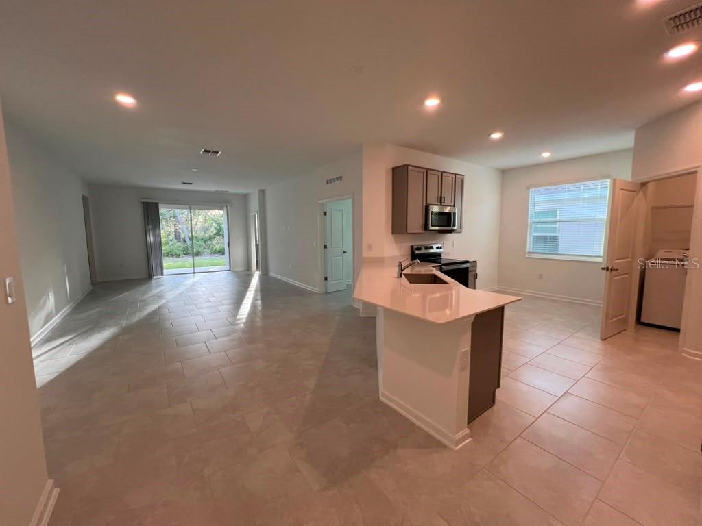 An open-concept kitchen with a breakfast bar overlooks a living area with sliding glass doors — 1378 PEACH CREEK DRIVE, OSTEEN, FL