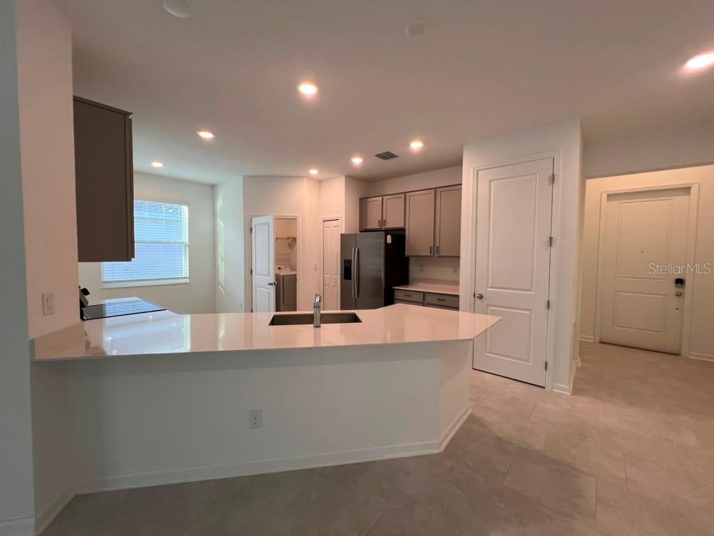 A kitchen with a white quartz island, grey cabinets, stainless steel appliances, and tile flooring — 1378 PEACH CREEK DRIVE, OSTEEN, FL