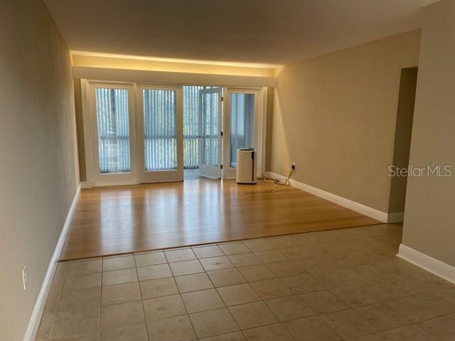 An interior view shows a room with tiled flooring, hardwood floors, and glass sliding doors — 200 N BETTY LANE UNIT 3E, CLEARWATER, FL