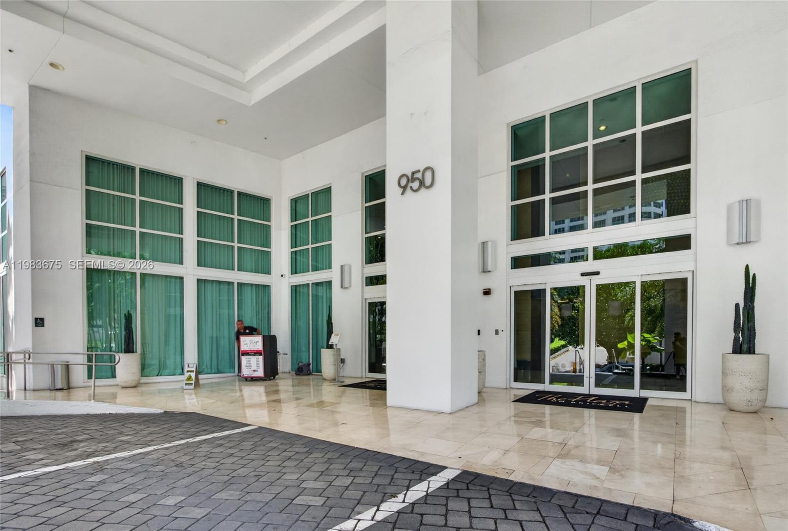 The exterior entrance of a modern white building features large glass windows and doors — 950 Brickell Bay Dr # 4100, Miami FL 33131, MIAMI, FL