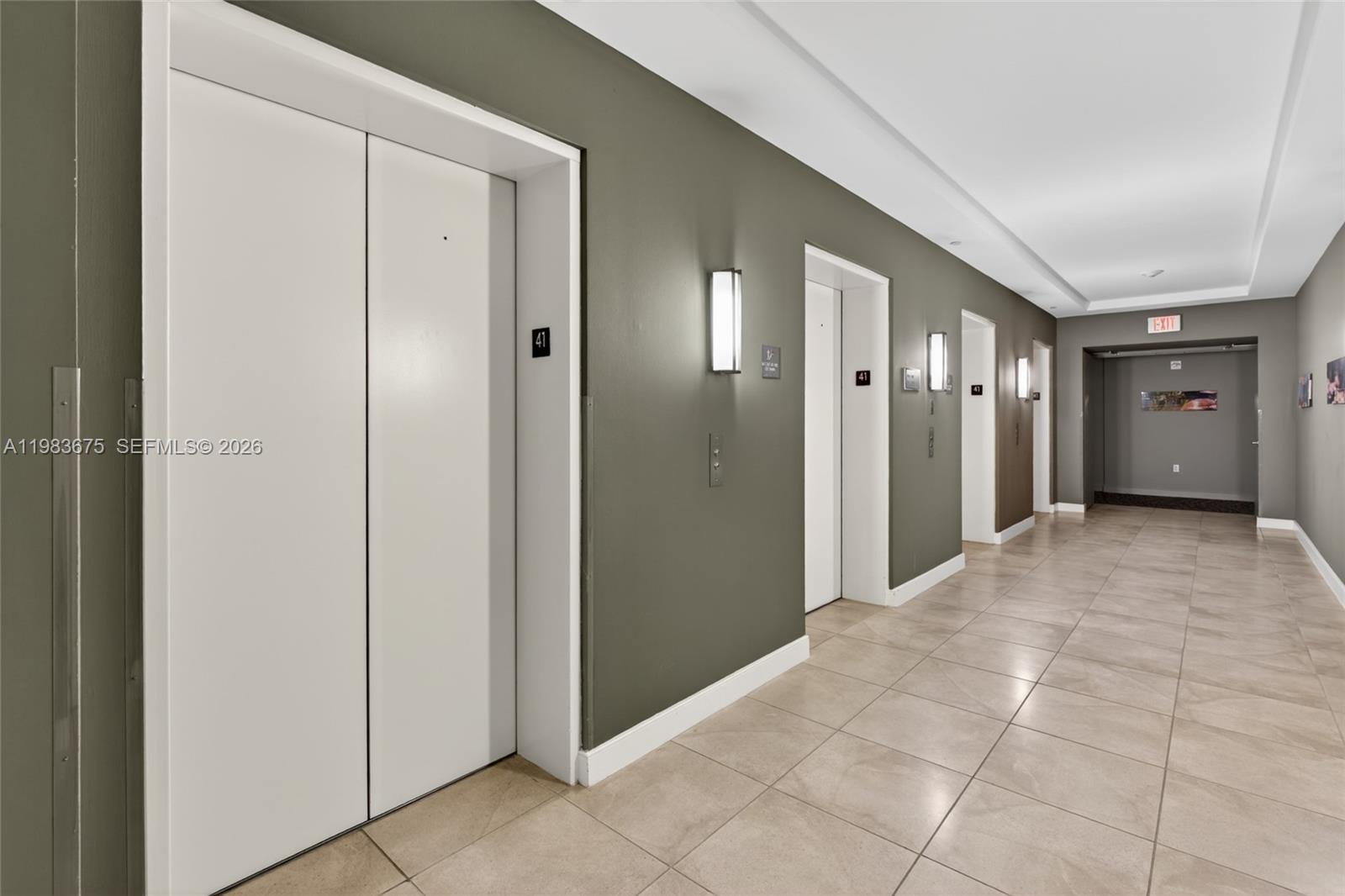 A hallway features tiled floors, gray walls, and several elevator doors with floor indicators — 950 Brickell Bay Dr # 4100, Miami FL 33131, MIAMI, FL