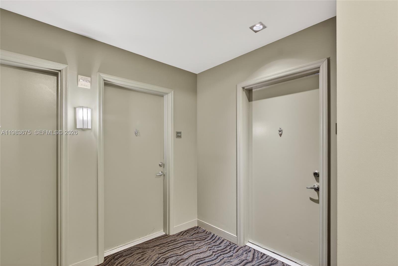 A hallway features two beige doors with silver hardware and patterned carpet flooring — 950 Brickell Bay Dr # 4100, Miami FL 33131, MIAMI, FL
