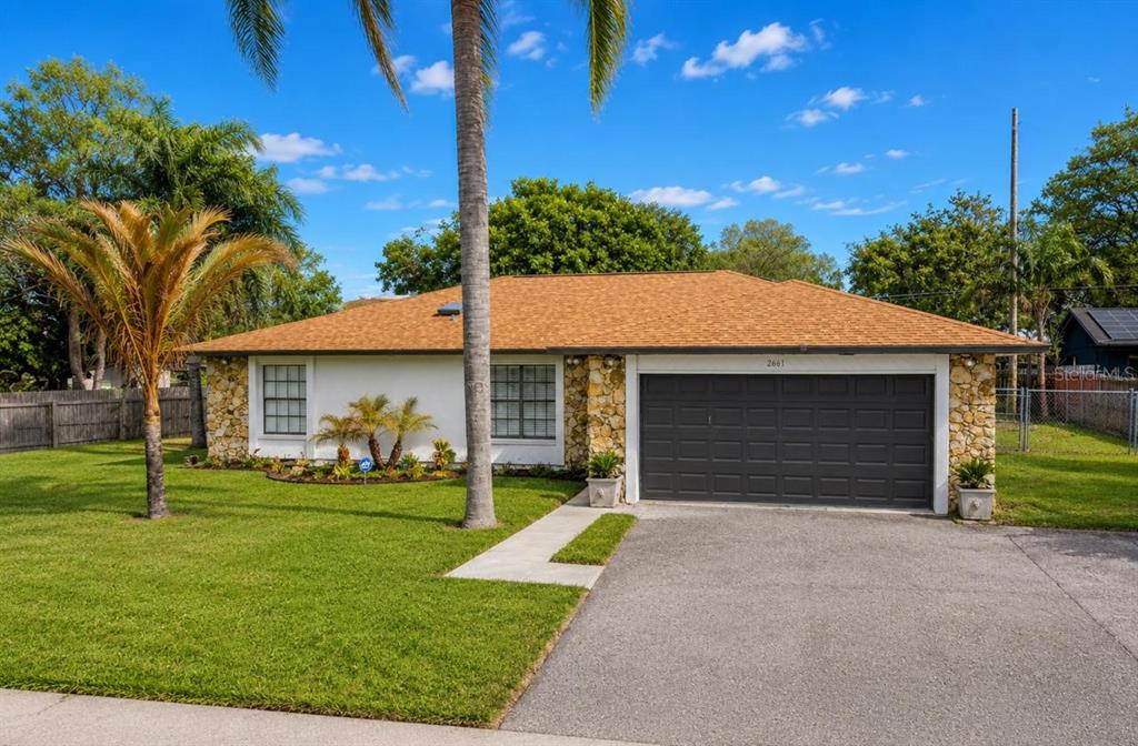 A single-story house with a stone facade, a brown shingled roof, and a two-car garage — 2661 AMES HAVEN ROAD, KISSIMMEE, FL