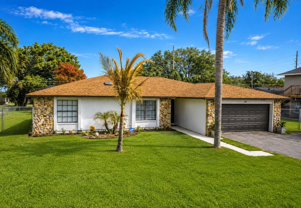 A single-story house with a white facade, stone accents, and a dark garage door — 2661 AMES HAVEN ROAD, KISSIMMEE, FL