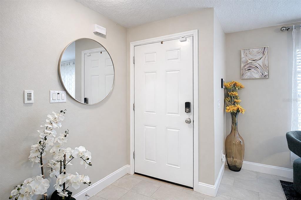An entryway features a white door, a round mirror, and a tall vase with flowers — 2661 AMES HAVEN ROAD, KISSIMMEE, FL