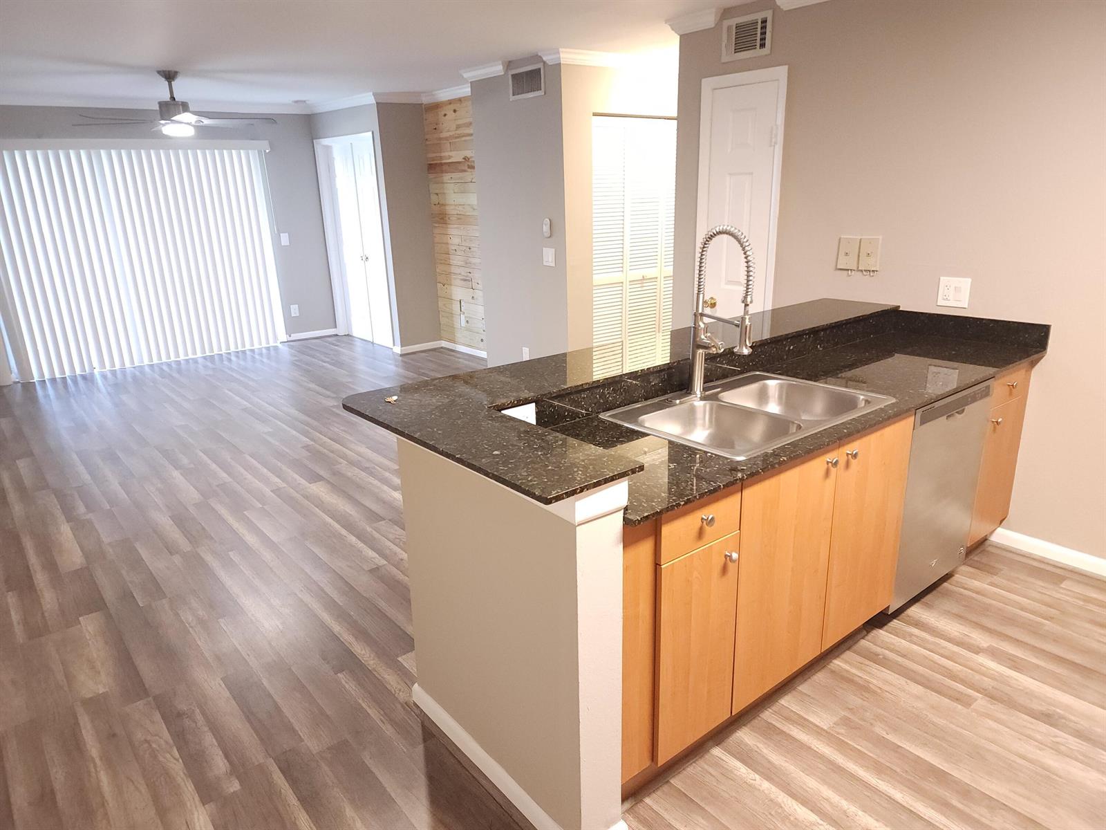 A kitchen with dark granite countertops and wood cabinets overlooks an open living area — 1740 Palm Cove Boulevard # 103, Delray Beach FL 33445, DELRAY BEACH, FL