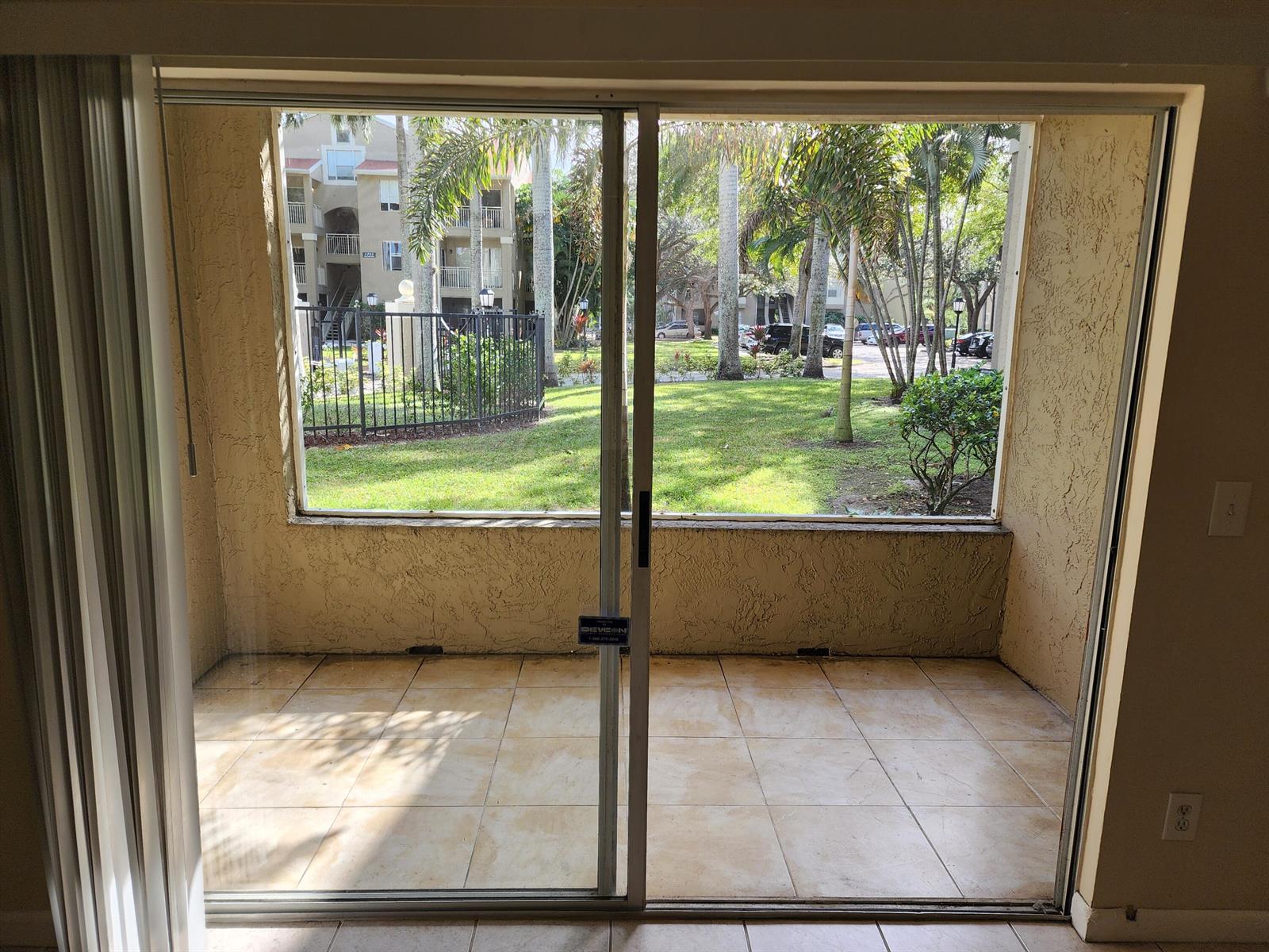 A hallway with light wood-look flooring leads to a doorway in a neutral-toned home — 1740 Palm Cove Boulevard # 103, Delray Beach FL 33445, DELRAY BEACH, FL