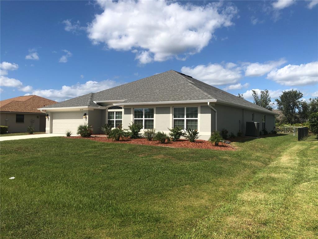 A single-story suburban house with a gray exterior, a shingled roof, and a two-car garage — 26332 BARRANQUILLA AVENUE, PUNTA GORDA, FL